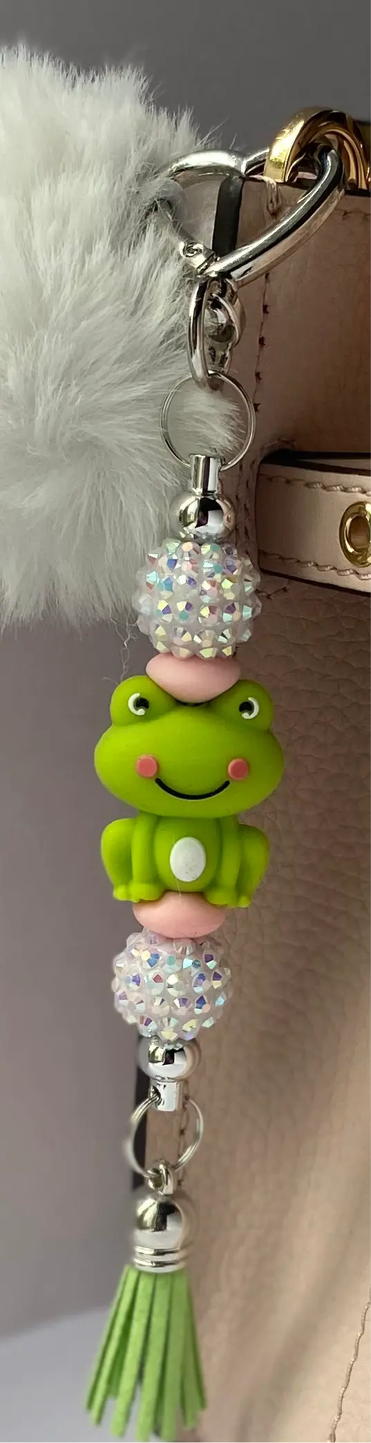 Beautiful keychain with a cute green frog and sparkling beads attached to a handbag.