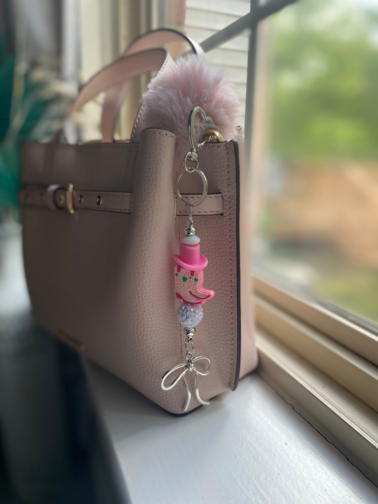Beautiful keychain bag charm on a stylish handbag by the window.