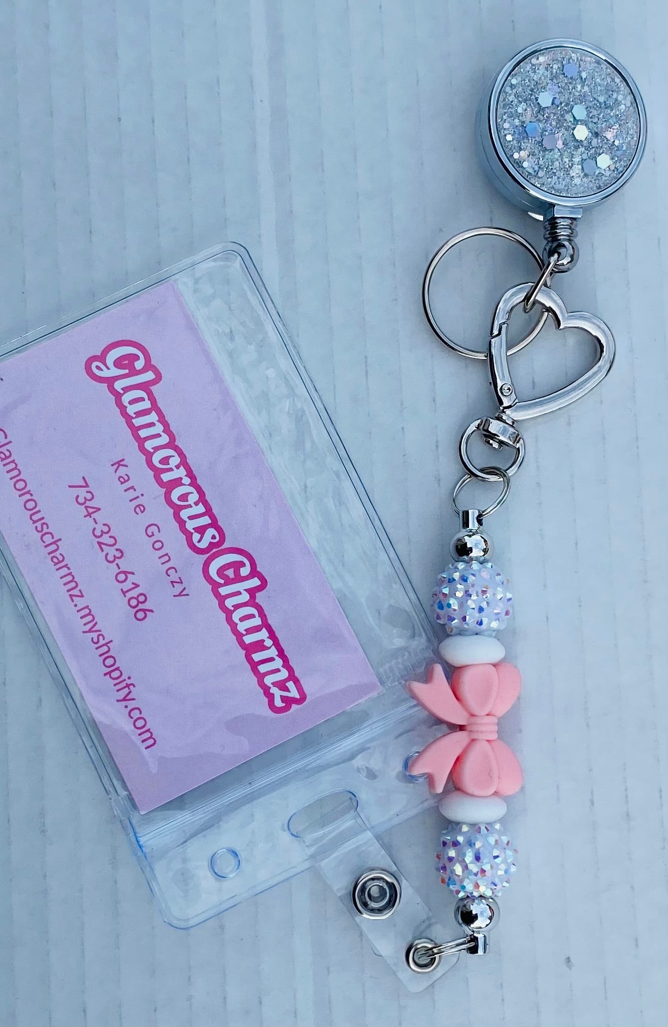 GlamorousCharmz keychain with decorative beads and a clear badge holder on a light gray background.