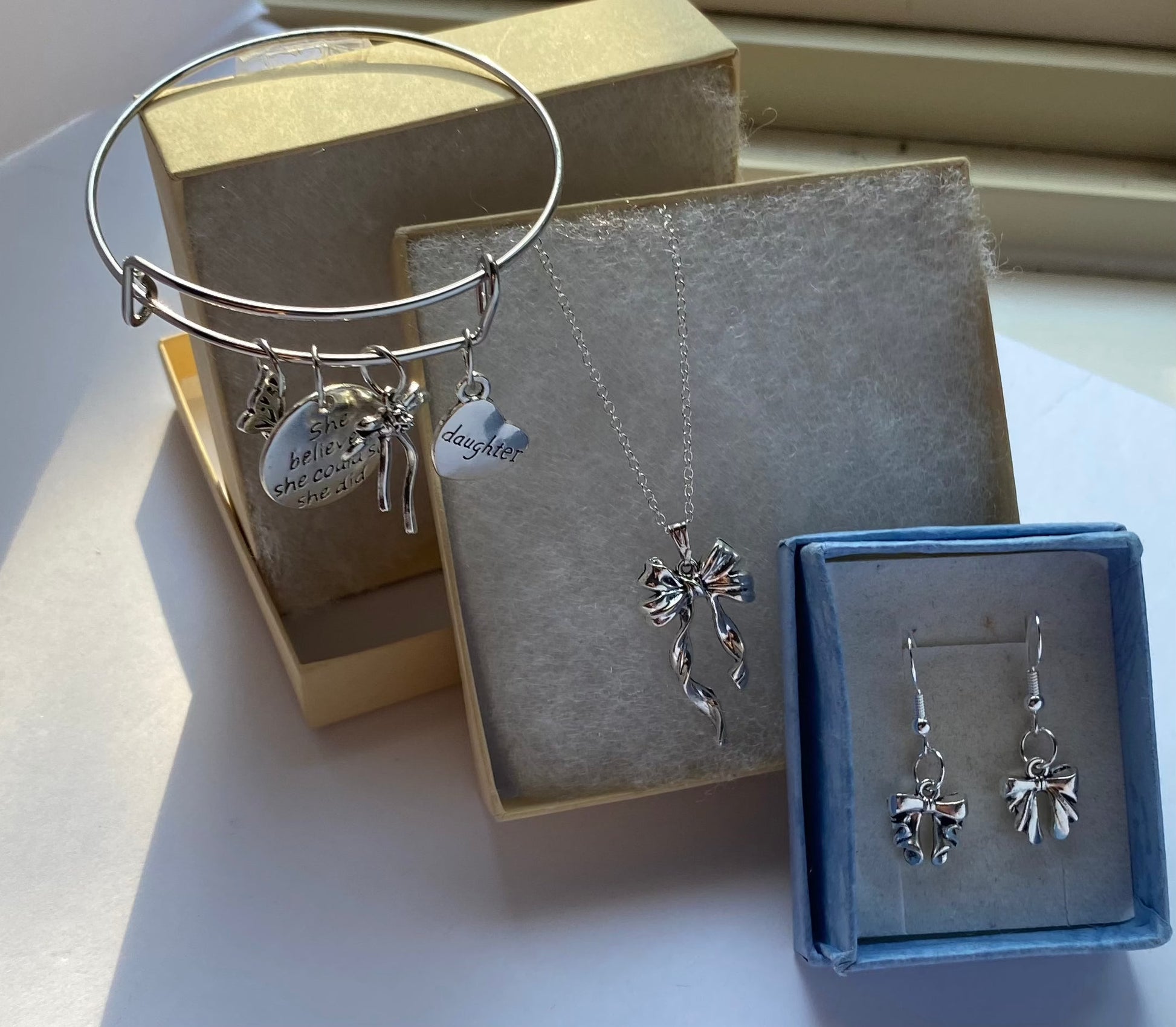 Gift full of emotion set with necklace, bow earrings, and charm bracelet for daughter.